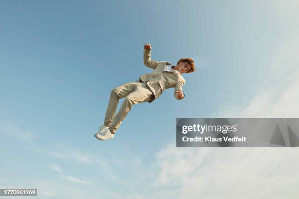 young man in mid-air against sky - cream coloured suit 個照片及圖片檔