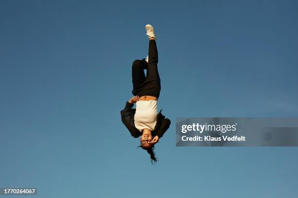 smiling woman levitating against blue sky - auf-den-kopf-gestellt stock-fotos und bilder