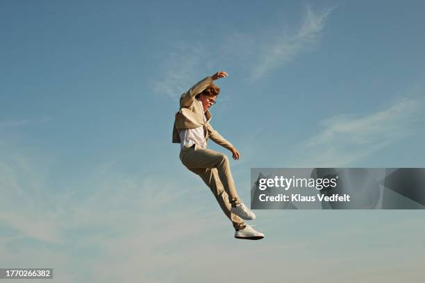 young man jumping while levitating in mid-air - cream coloured suit 個照片及圖片檔