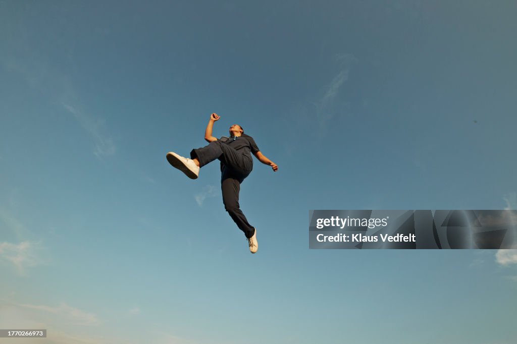 Female nurse posing in mid-air against sky