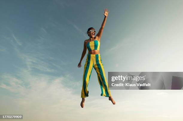 woman levitating while raising hand against sky - gymnastic asian stockfoto's en -beelden