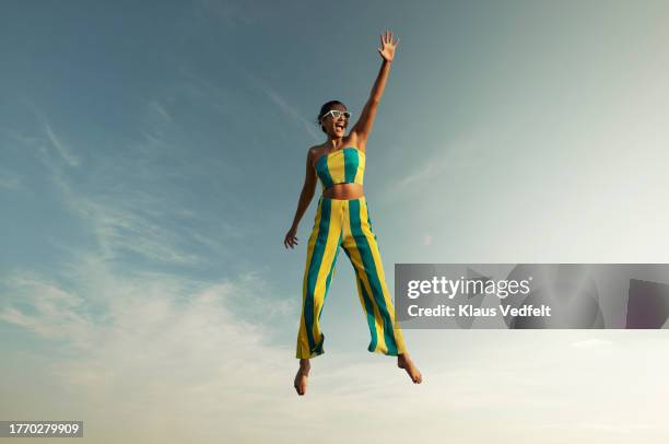 woman levitating while raising hand against sky - high arm stock pictures, royalty-free photos & images