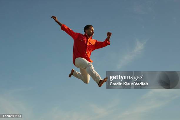 man jumping high and posing against sky - agile transformation stock pictures, royalty-free photos & images