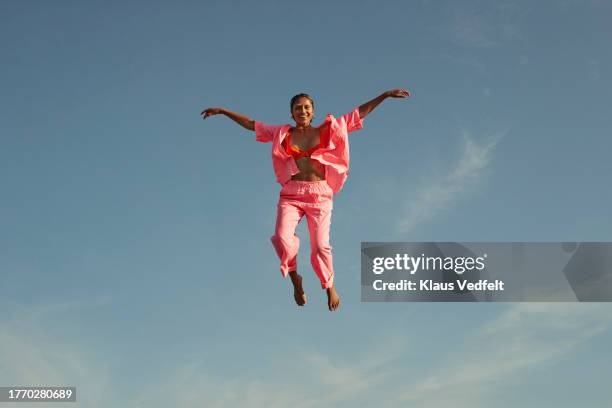 smiling woman with arms outstretched in mid-air - agility stock pictures, royalty-free photos & images