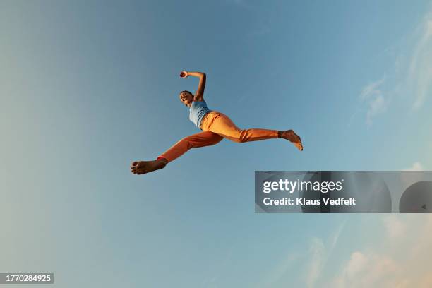 smiling woman jumping with legs apart - leap of faith activity stock pictures, royalty-free photos & images