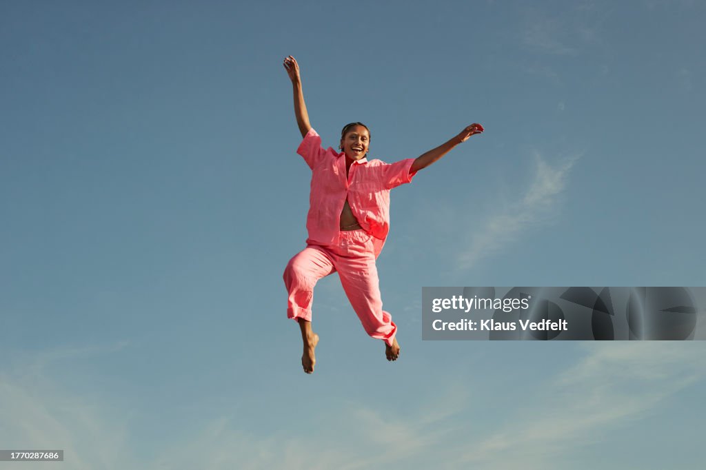 Happy woman jumping high against sky