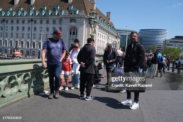 An entertainer on Westminster Bridge with London tourists involving the three cups magic trick on June 2, 2023 in London, United Kingdom. Gangs have...