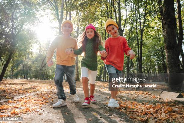 children in colorful sweaters run in the park. inclusion - inclusion body stock-fotos und bilder