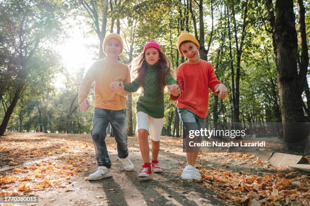 children in colorful sweaters run in the park. inclusion - inclusion body stock pictures, royalty-free photos & images