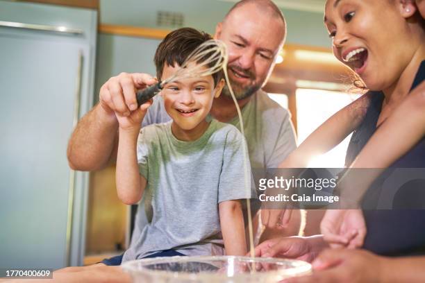 happy boy with down syndrome baking with family at home - familie anonym stock-fotos und bilder
