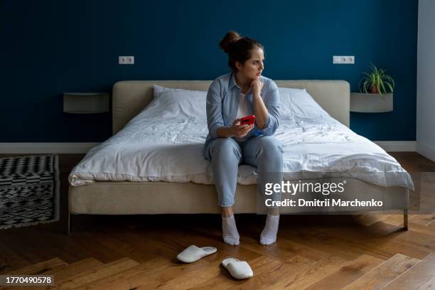 body positive plus size serious woman sitting in modern flat thinking on diet, exercise, calories - flat stomach stock-fotos und bilder