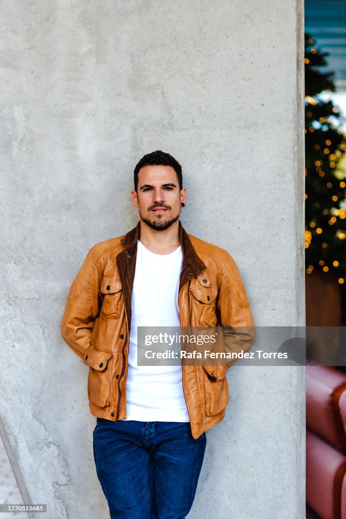 Young handsome man in leather jacket leaning on a wall outdoor