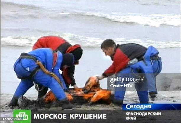 Russian NTV channel television grab shows Russian rescuers as they collect the dead body of a sailor on the beach on the Black Sea shore in Port...