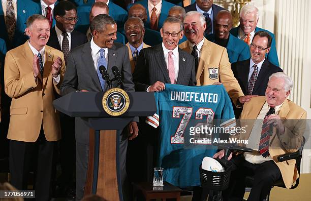 First row, U.S. President Barack Obama is presented with a jersey by current team owner Stephen Ross as members of the 1972 Miami Dolphins, head...