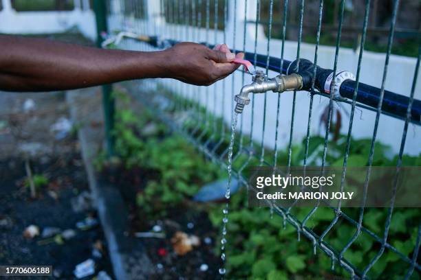 Man fills a a bucket with water at an access point in Dzaoudzi, on the French Indian Ocean island of Mayotte on November 7, 2023. In response to the...