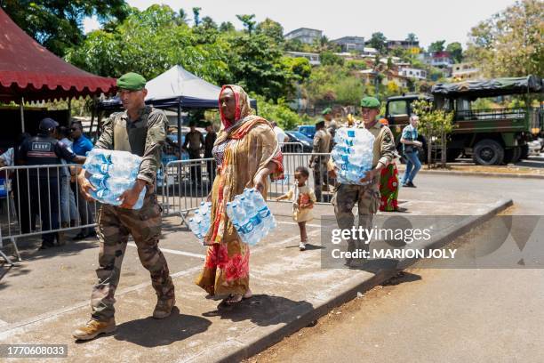 French soldier helps local residents to carry bottles of mineral water as water is being distributed to the most vulnerable in Cavani neighbourhood...