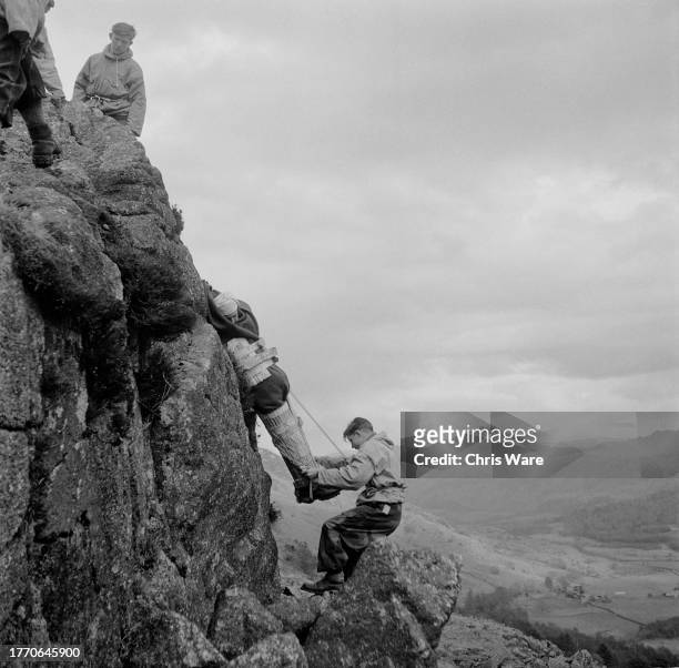 Teenage boys descending a rockface during a mountain rescue practice near the Outward Bound Mountain School at Eskdale Green, Cumbria, April 1950....