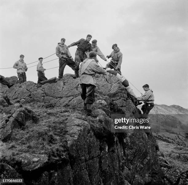 Teenage boys descending a rockface during a mountain rescue practice near the Outward Bound Mountain School at Eskdale Green in Cumbria, April 1950....