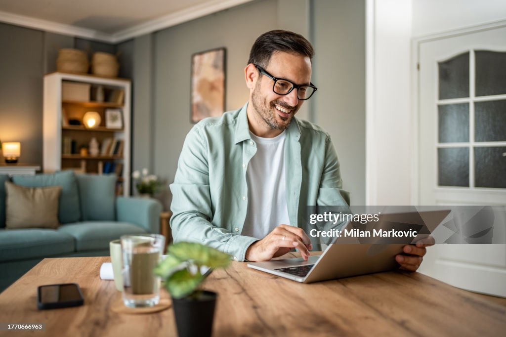 Retrato de un hombre caucásico guapo mirando una computadora portátil, trabajando en línea desde su casa