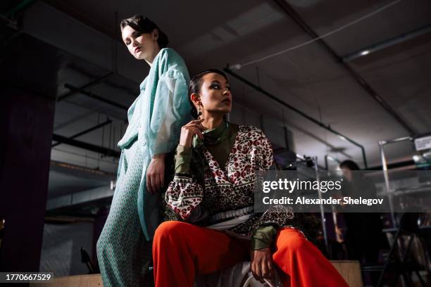 group female portrait of two fashion models indoors. behind the scenes of fashion week show, backstage photography. women behind the catwalk wear design clothing. lifestyle photo with beauty people. - fashionshows stockfoto's en -beelden