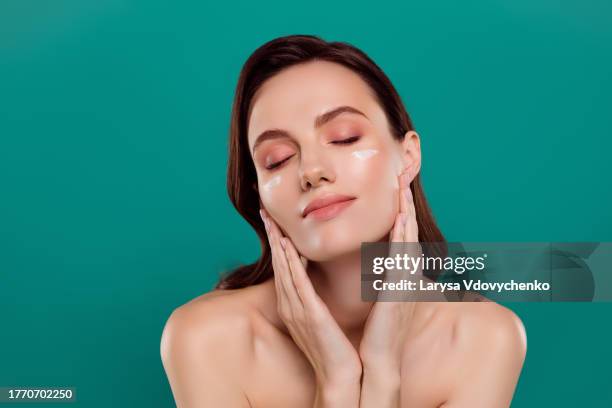 photo portrait of attractive young woman apply cream cheeks touch neck spa salon isolated on cyan color background - gesicht kosmetik maske stock-fotos und bilder