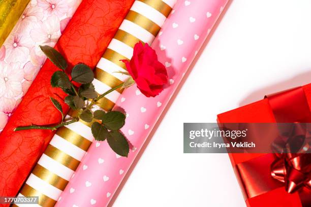 holidays multi colorful wrapping paper rolls, red rose flower and red gift box on white color background. - christmas wrapping paper rolls stock pictures, royalty-free photos & images