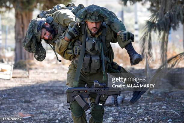 An Israeli soldier carries a comrade as they train while keeping a position in the upper Galilee region of northern Israel near the border with...
