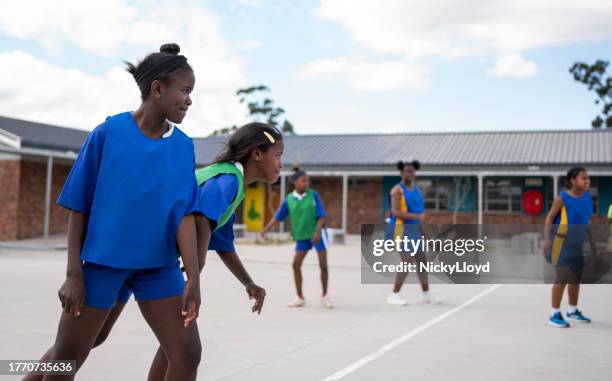 netball girls team playing a game in school gym - black children stock pictures, royalty-free photos & images