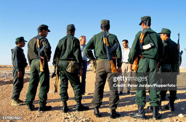 Armed guards are briefed before patrolling a perimeter fence surrounding a compound housing Bechtel construction workers building the Maghreb-Europe...