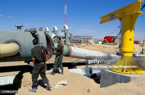 Armed guards check installed pipework during construction of the Maghreb-Europe Gas Pipeline in the desert interior of Algeria in September 1995. The...