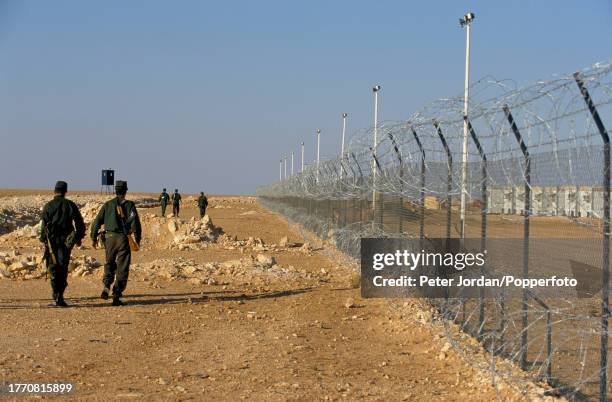 Armed guards patrol a perimeter fence surrounding a compound housing Bechtel construction workers building the Maghreb-Europe Gas Pipeline in the...