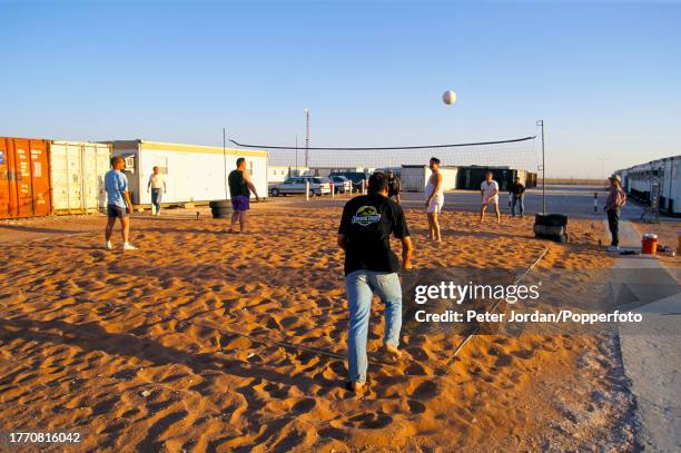 Employees play a game of beach volleyball in a compound housing Bechtel construction workers building the Maghreb-Europe Gas Pipeline in the desert...
