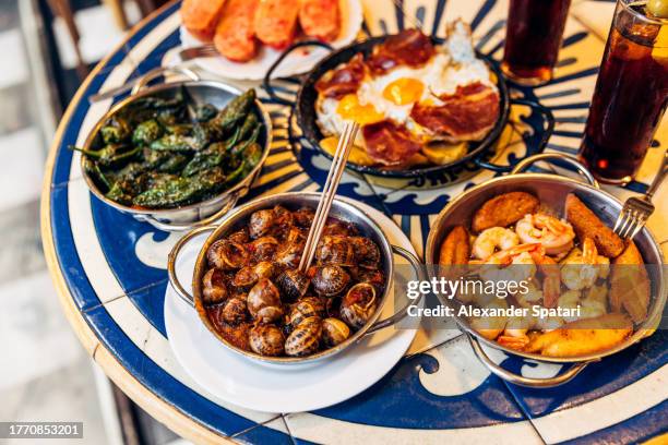 caracoles snails, shrimps with garlic and padron peppers served in spanish tapas restaurant, barcelona, spain - comida francesa fotografías e imágenes de stock