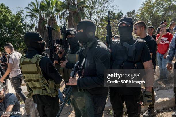 Masked Hamas militiamen carry their weapons during the funeral of four young men killed by the Israeli army in a raid on the town of Tulkarm. Four...