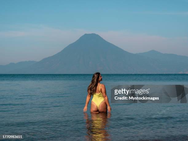 young woman in swimwear entering the lake, volcano view - lake atitlan stock pictures, royalty-free photos & images