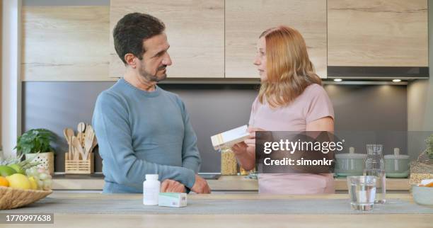frau hält medikamentenbox, während sie mit einem mann spricht - pillenbox stock-fotos und bilder