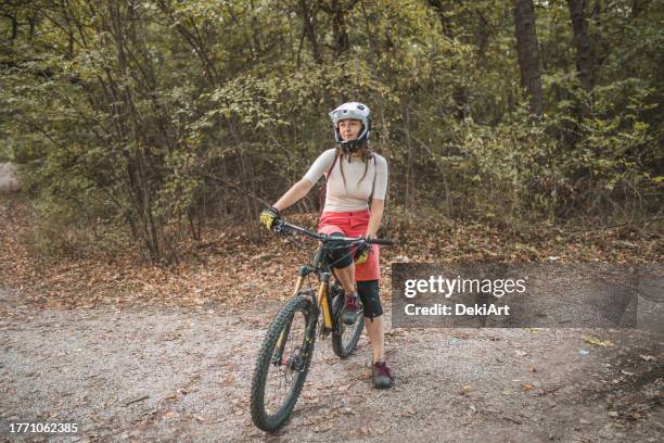 female mountain biker riding downhill, enjoying on ride and living adventure in the mountain - protective sportswear stock pictures, royalty-free photos & images