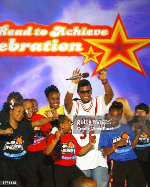 Singer Usher and kids sing and dance onstage during the NBA All-Star Jam Session event "Read to Achieve" celebration on February 8, 2003 at the...