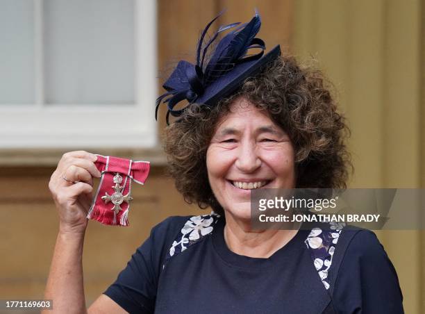 Writer Francesca Simon poses with their medal after being appointed a Member of the Order of the British Empire following an investiture ceremony at...