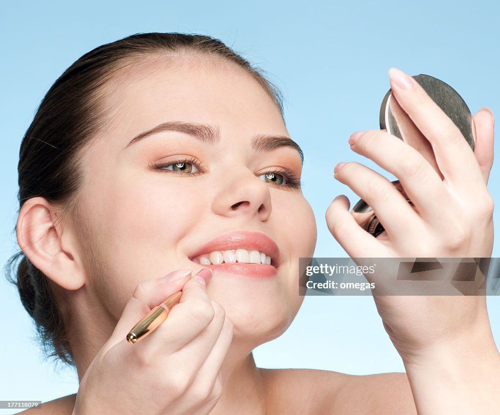 Beautiful young adult woman applying cosmetic lipstick pencil