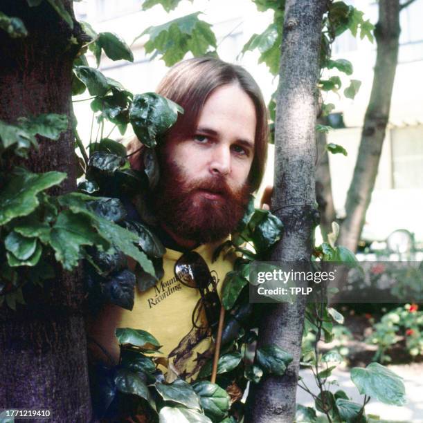 Portrait of American Pop musician Carl Wilson , of the group the Beach Boys, as he poses behind a tree, London, England, June 23, 1977.