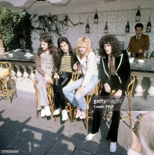 View of members of the Rock and Pop group Queen as they pose at an outdoor bar, London, England, September 8, 1976. Pictured are, from left, John...