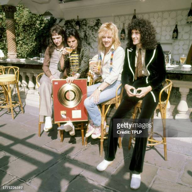 View of members of the Rock and Pop group Queen as they pose with a Gold record , London, England, September 8, 1976. Pictured are, from left, John...