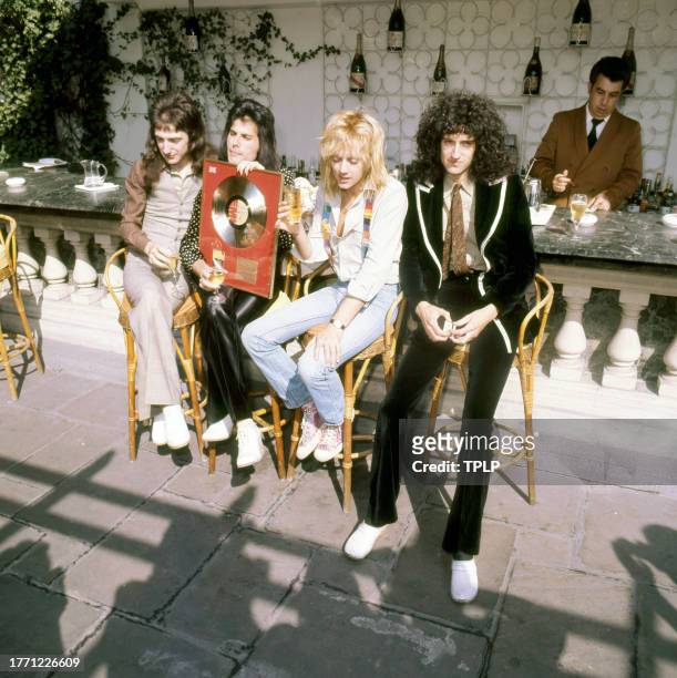 View of members of the Rock and Pop group Queen as they pose with a Gold record , London, England, September 8, 1976. Pictured are, from left, John...