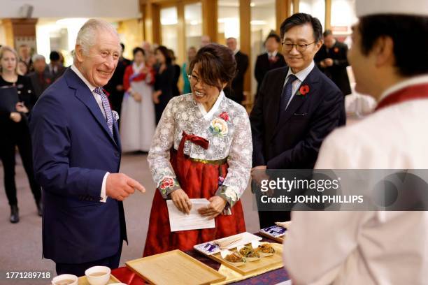 Britain's King Charles III talks with a chef as his is shown a presentation of Korean food, during a visit to New Malden Methodist Church in New...