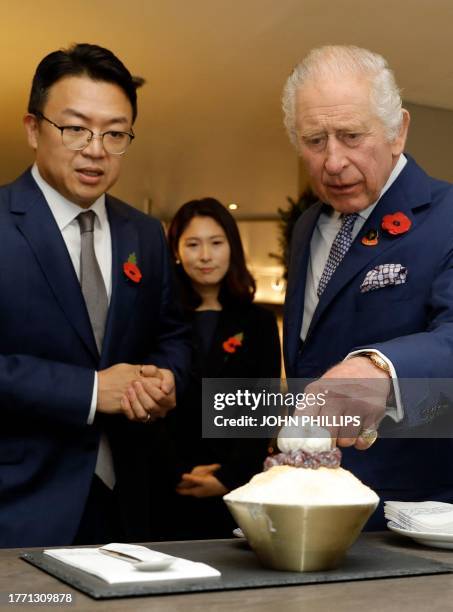 Britain's King Charles III talks with owners of the Cake & BingSoo Shop Kim Jong-soon and Jun So-you during a visit to their shop, in New Malden,...