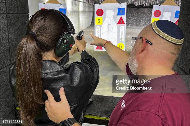 An instructor assists a participant using a handgun during a training session at a shooting range in Pompano Beach, Florida, US, on Wednesday, Oct....