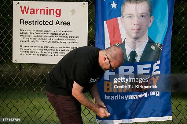 Michael McKee mounts a sign on a fence as protesters with the Bradley Manning Support Network hold a vigil while waiting to hear Manning's sentence...