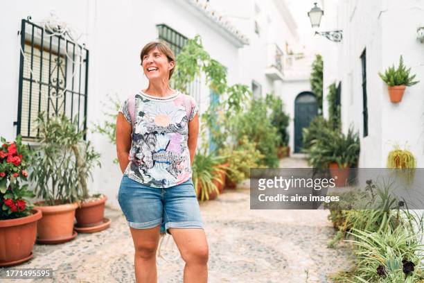 portrait of a beautiful tourist woman standing in the streets of frigiliana outside the houses, front view - frigiliana stock pictures, royalty-free photos & images