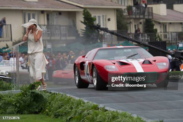 Presenter covers her ears as a 1966 Ford GT40 mark 1 drives over the ramp during the 2013 Pebble Beach Concours d' Elegance in Pebble Beach,...